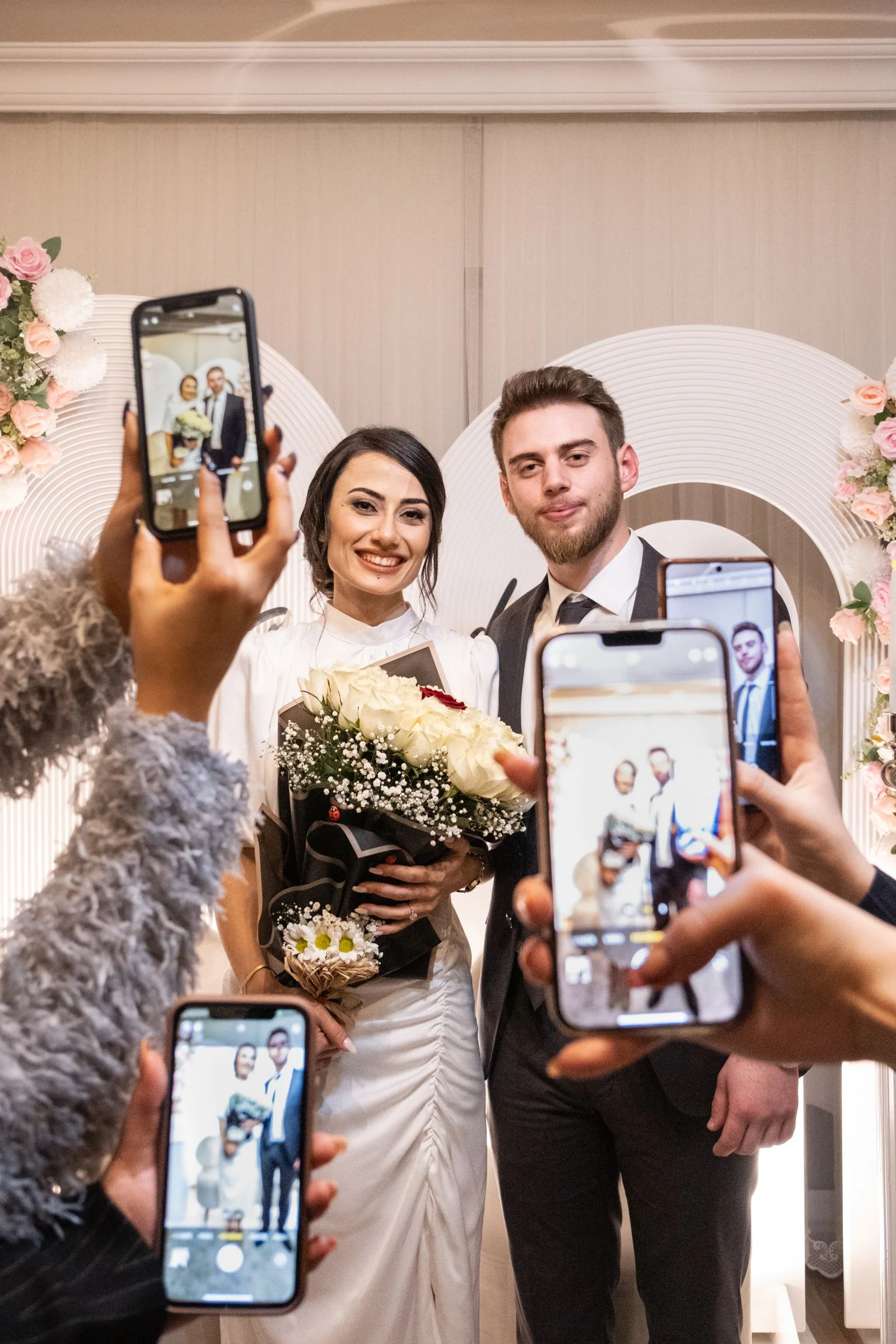 Wedding guests photographing newlyweds with smartphones