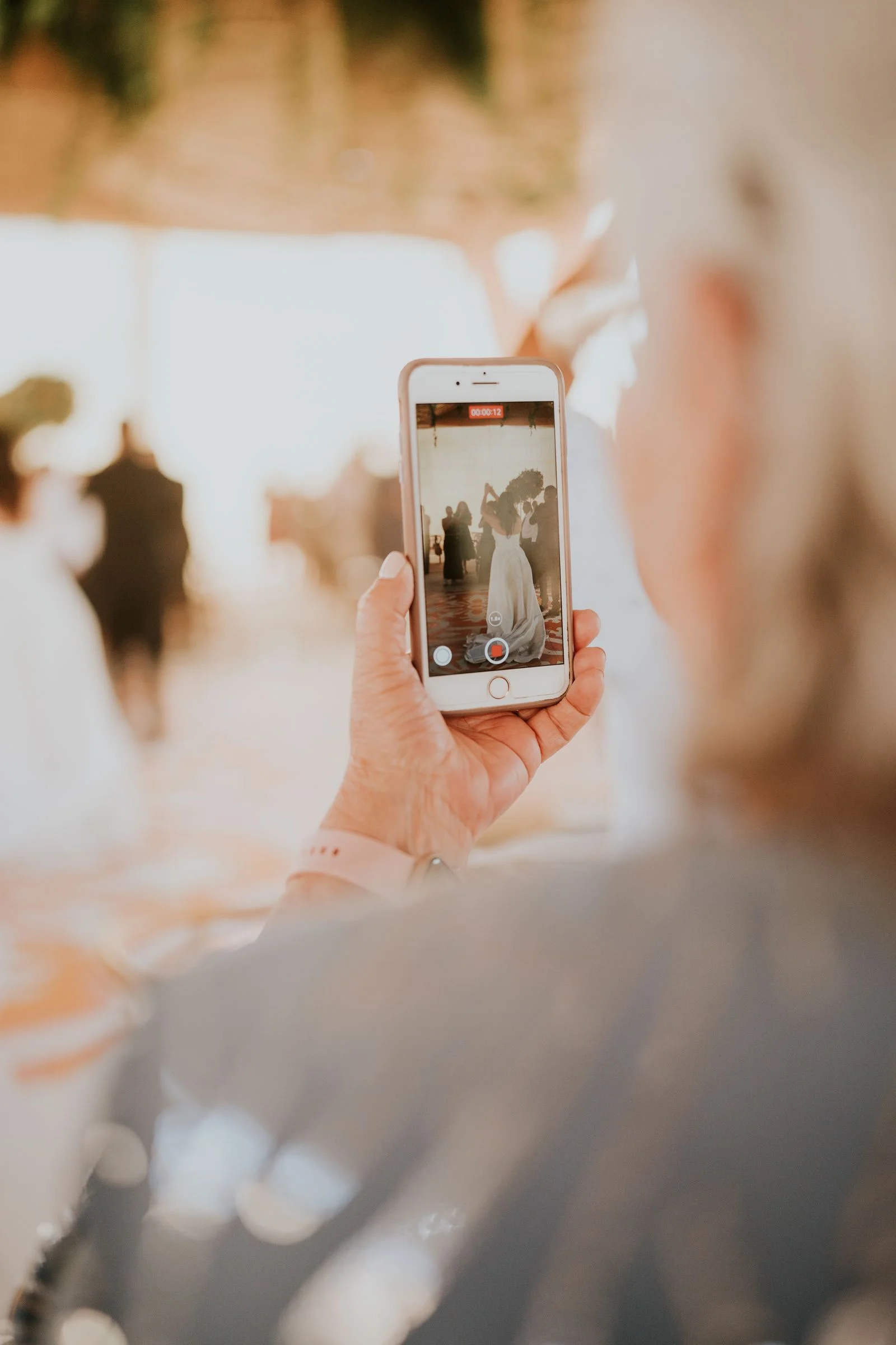 Older wedding guest taking a photo with a smartphone