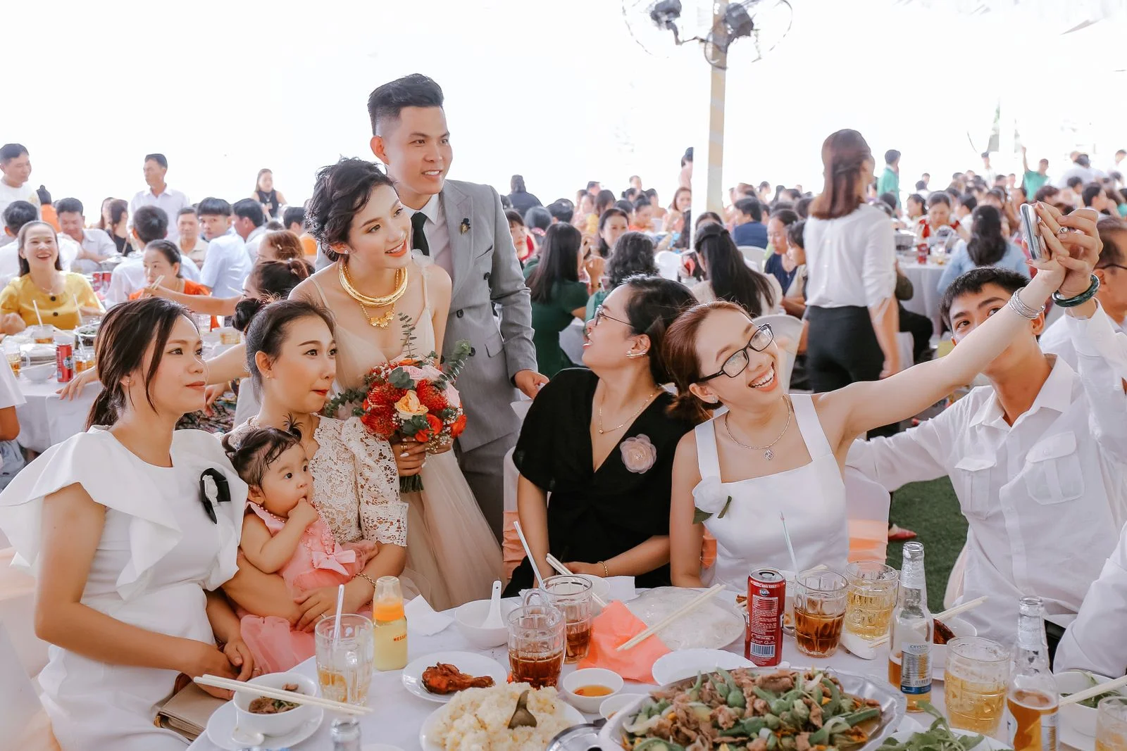 Newlyweds and friends taking a group selfie at a wedding reception